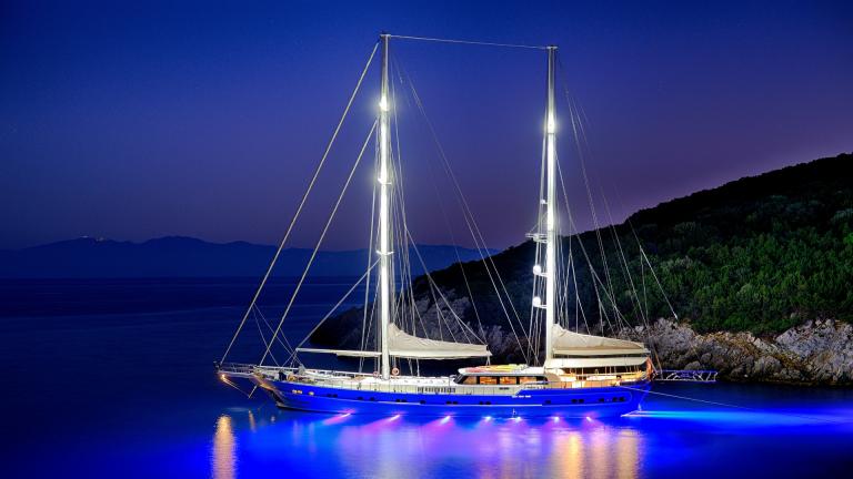 Luxury gulet in the bay at night, blue lights on